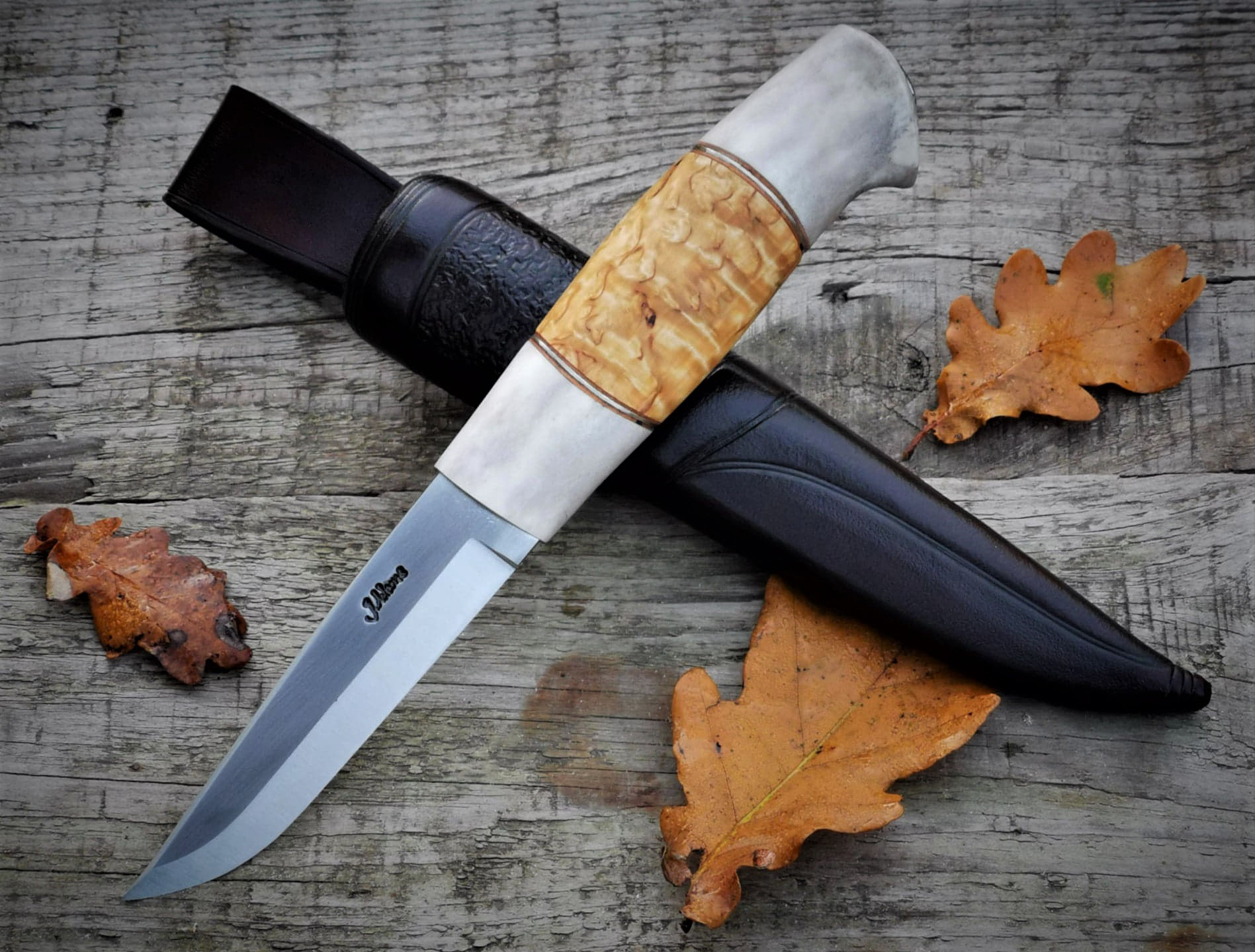 Puukko mit Birkengriff zwischen Herbstblättern